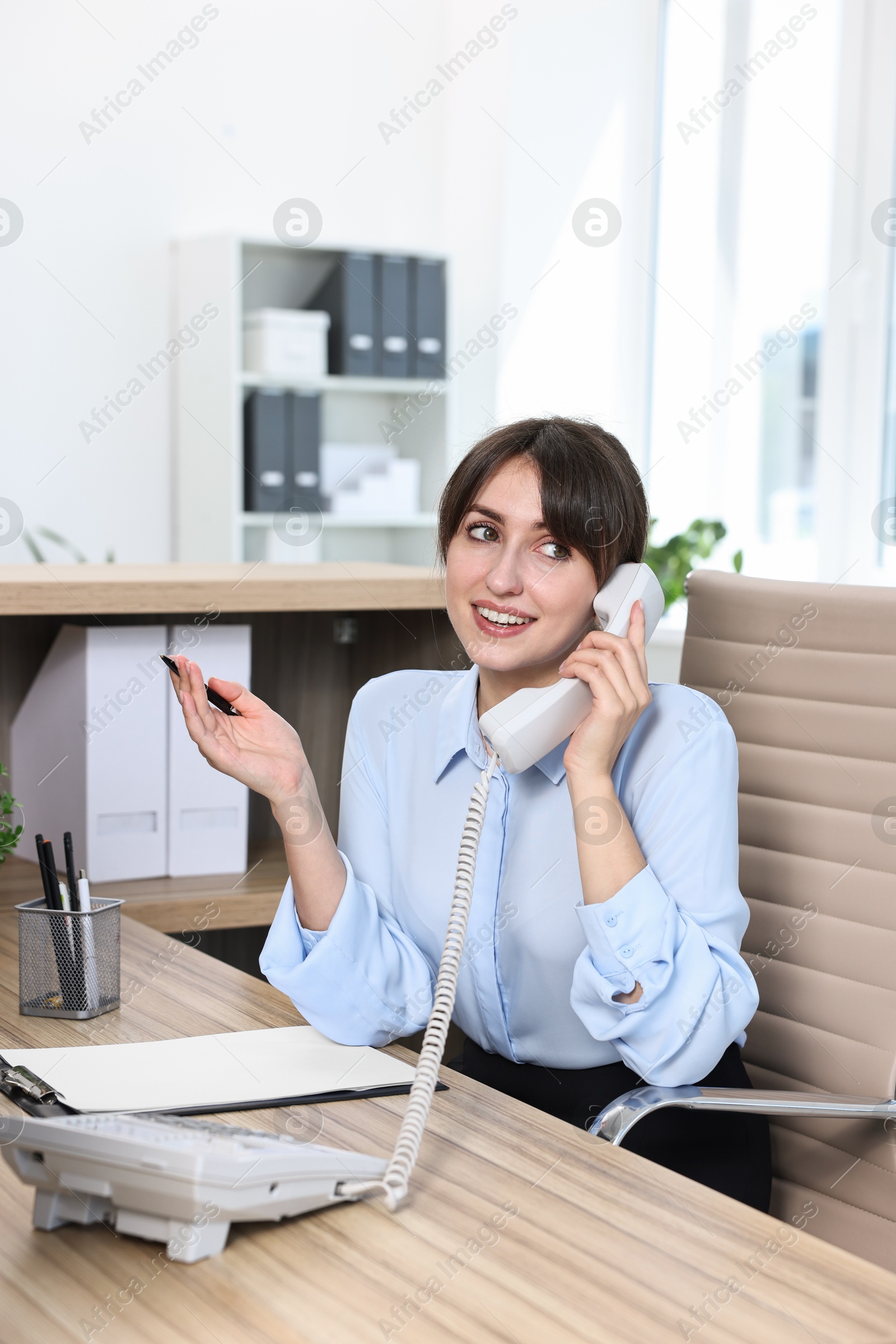 Photo of Professional receptionist talking on phone in office