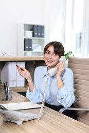 Professional receptionist talking on phone in office