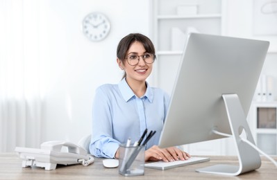 Photo of Professional receptionist working at wooden desk in office