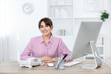 Portrait of receptionist at wooden desk in office