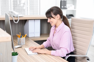 Professional receptionist working at wooden desk in office