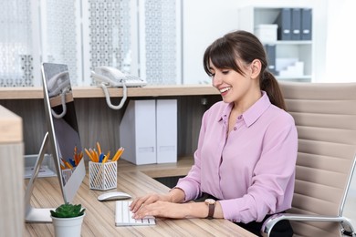 Professional receptionist working at wooden desk in office