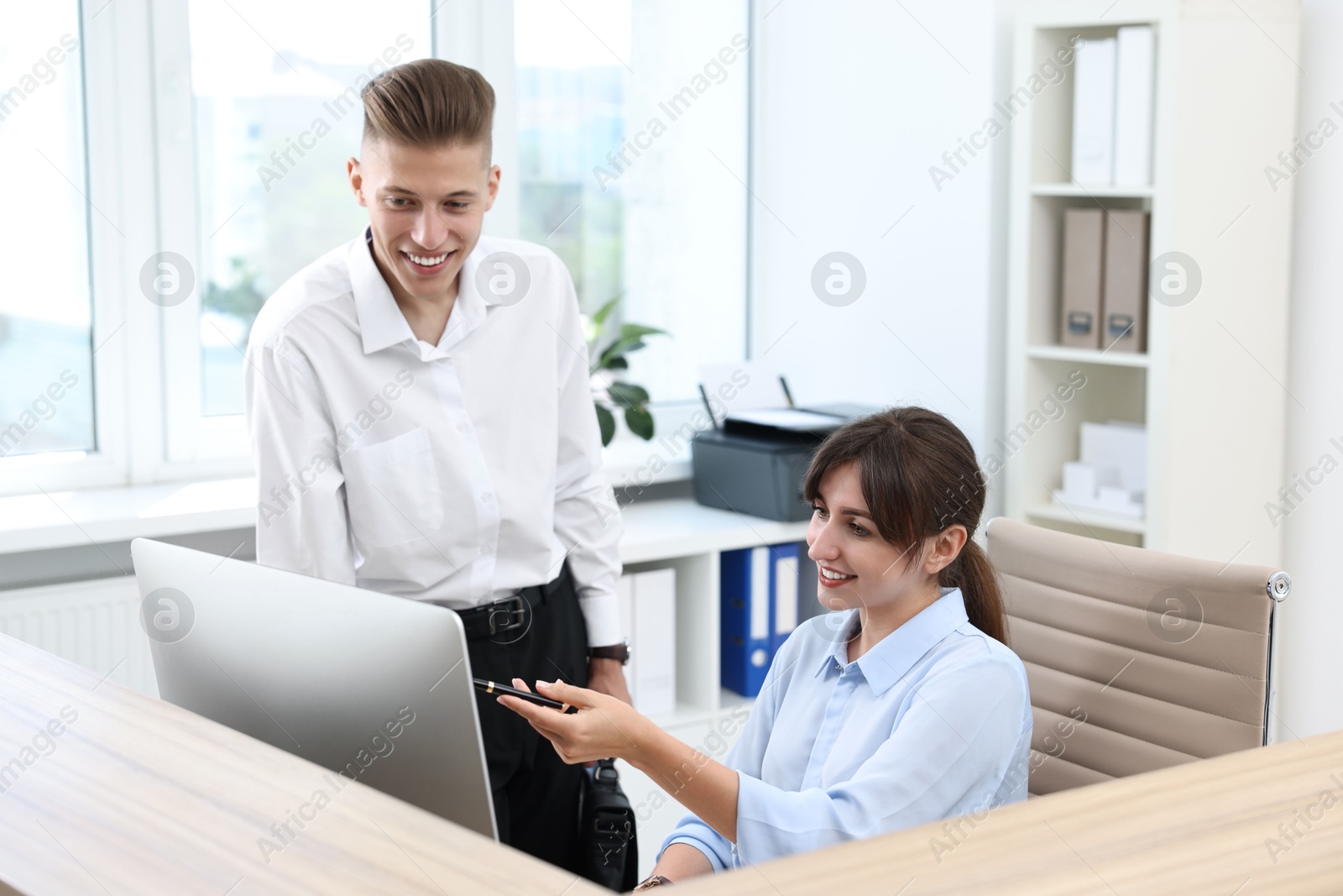 Photo of Professional receptionist working with client in office