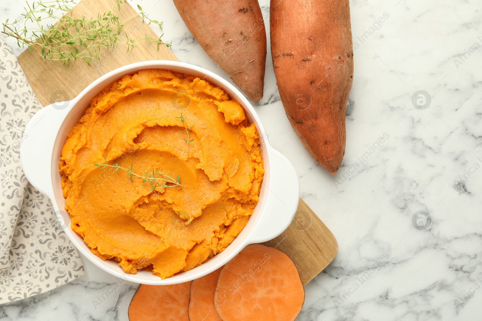 Photo of Delicious mashed sweet potatoes in pot, vegetables and microgreens on white marble table, top view