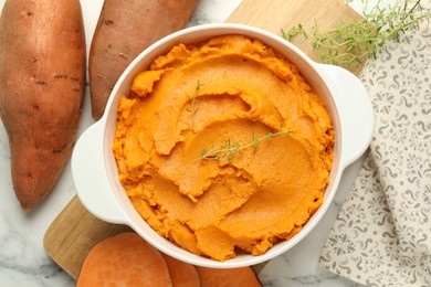 Delicious mashed sweet potatoes in pot, vegetables and microgreens on white marble table, top view