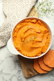 Delicious mashed sweet potatoes in pot, vegetables and microgreens on white marble table, top view