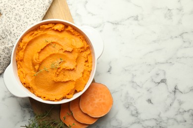 Delicious mashed sweet potatoes in pot, vegetables and microgreens on white marble table, top view. Space for text