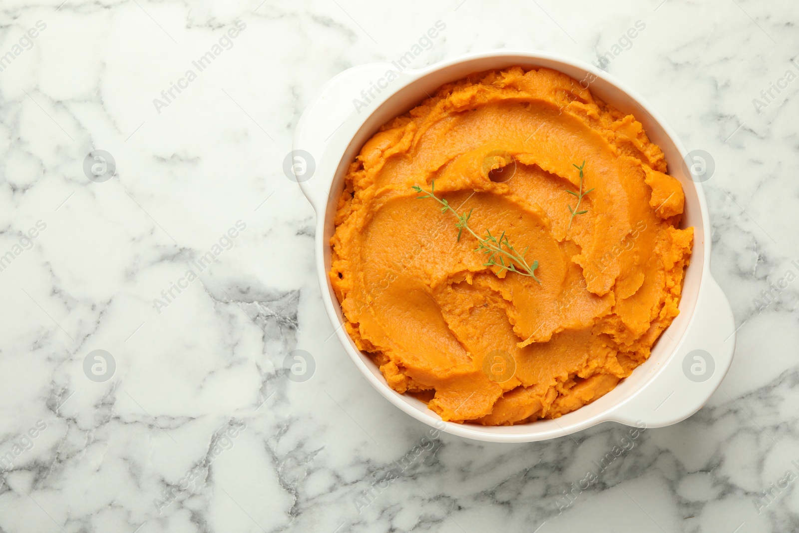 Photo of Delicious mashed sweet potatoes in pot on white marble table, top view. Space for text