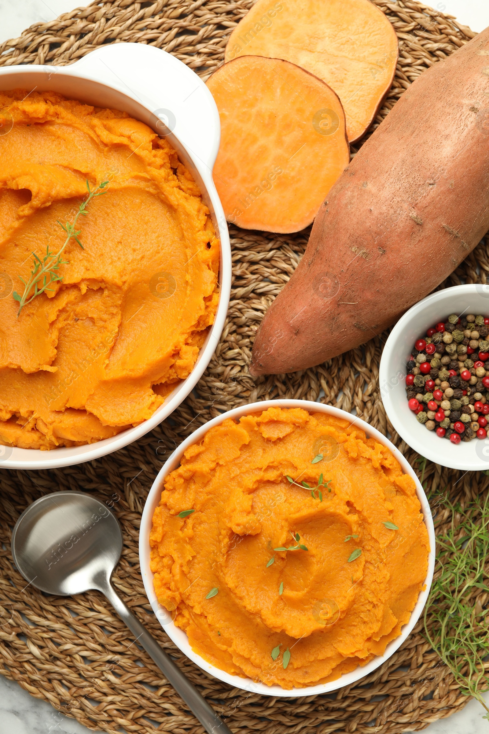 Photo of Delicious mashed sweet potatoes, spoon, microgreens, spices and vegetables on table, top view