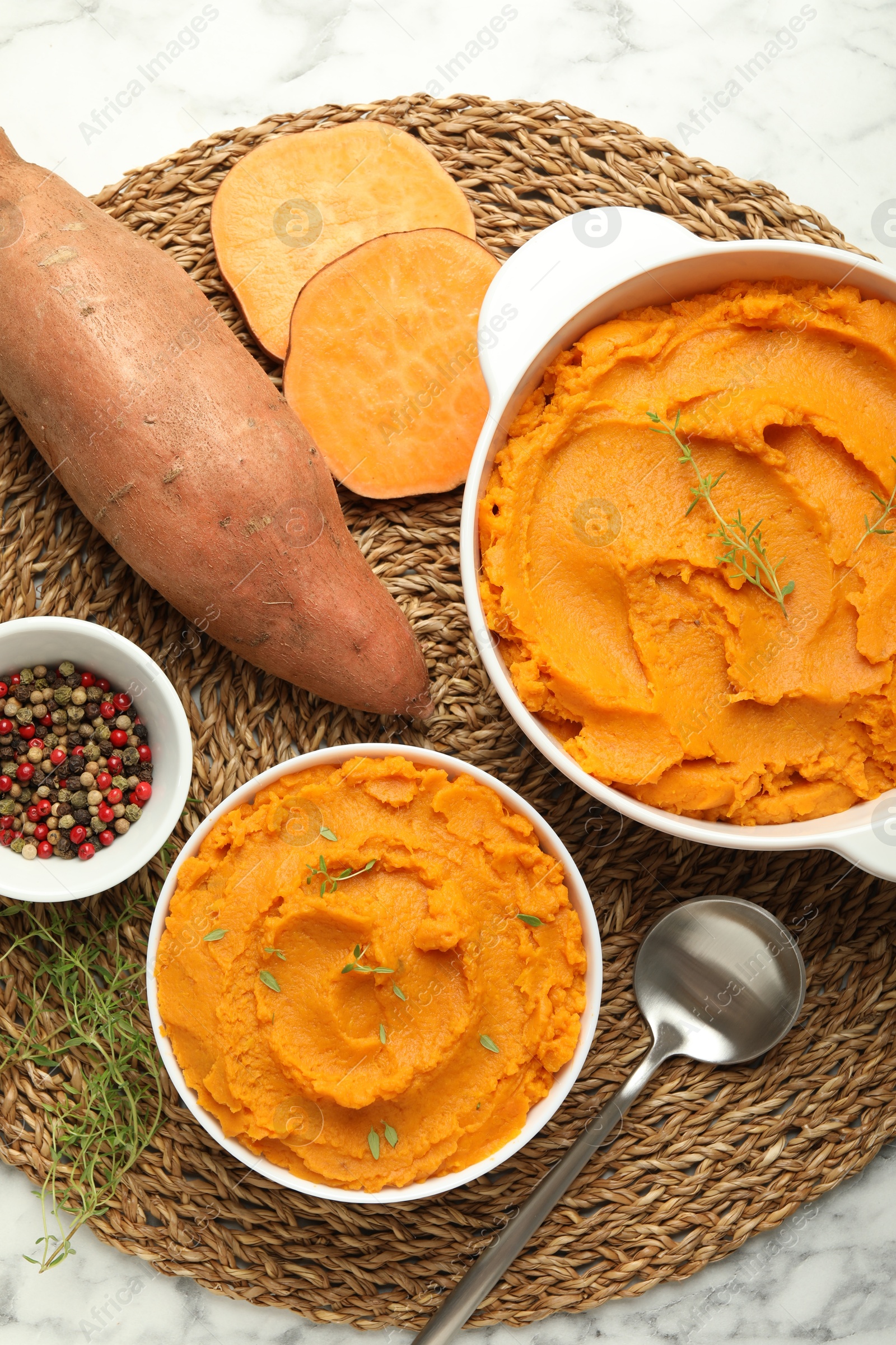 Photo of Delicious mashed sweet potatoes, spoon, microgreens, spices and vegetables on white marble table, top view