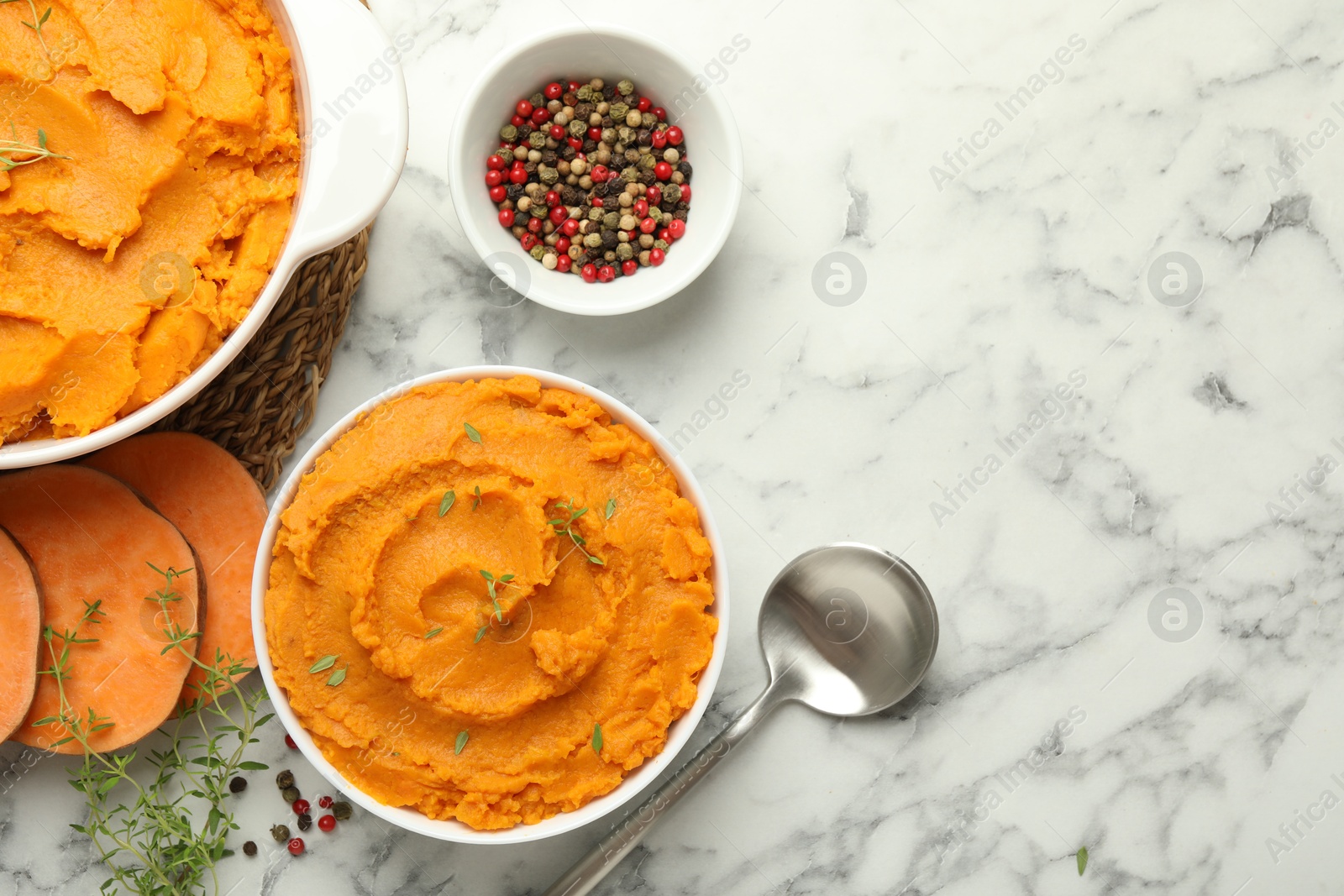 Photo of Delicious mashed sweet potatoes, spoon, microgreens, spices and vegetables on white marble table, top view. Space for text