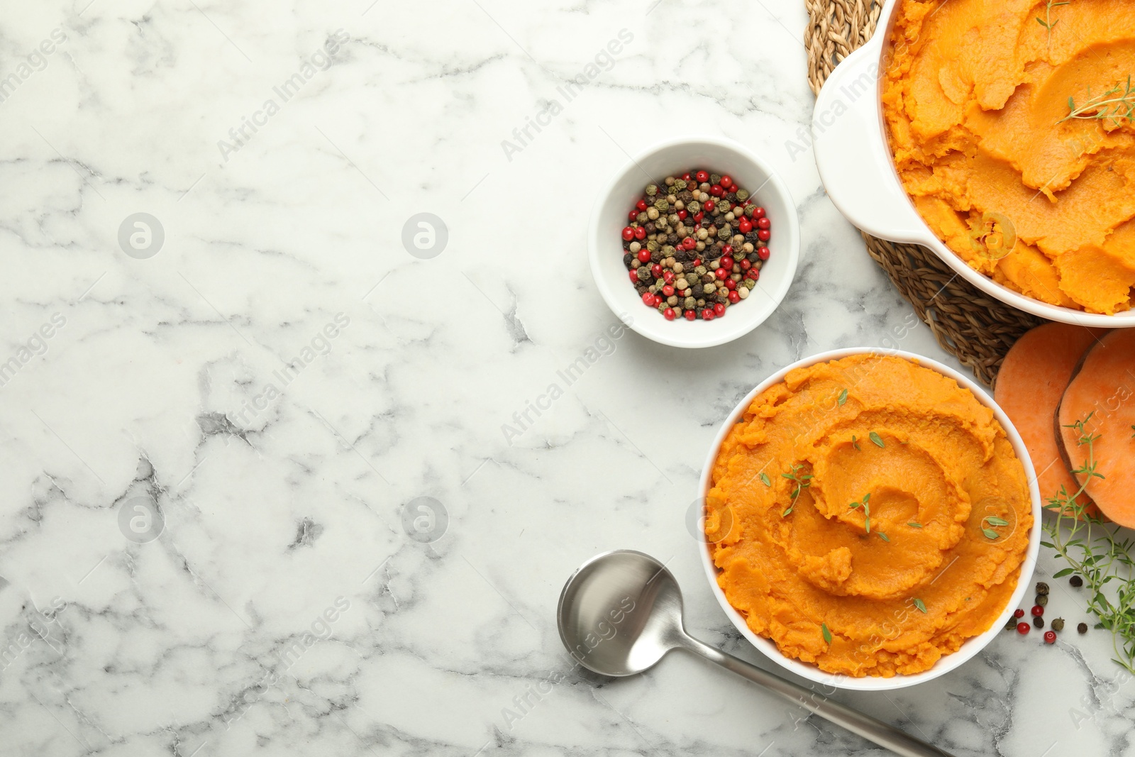 Photo of Delicious mashed sweet potatoes, spoon, microgreens, spices and vegetables on white marble table, top view. Space for text