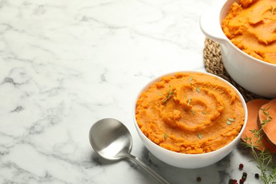 Photo of Delicious mashed sweet potatoes, spoon, microgreens, spices and vegetable on white marble table, space for text