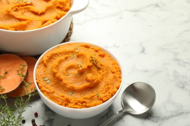 Photo of Delicious mashed sweet potatoes, spoon, microgreens, spices and vegetable on white marble table