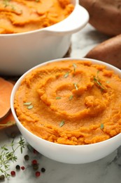 Photo of Delicious mashed sweet potatoes in bowl and spices on white marble table, closeup