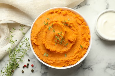 Photo of Delicious mashed sweet potatoes in bowl, microgreens, sour cream and spices on white marble table, top view