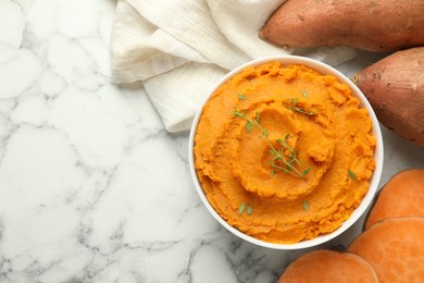 Photo of Delicious mashed sweet potatoes in bowl, microgreens and vegetables on white marble table, top view. Space for text