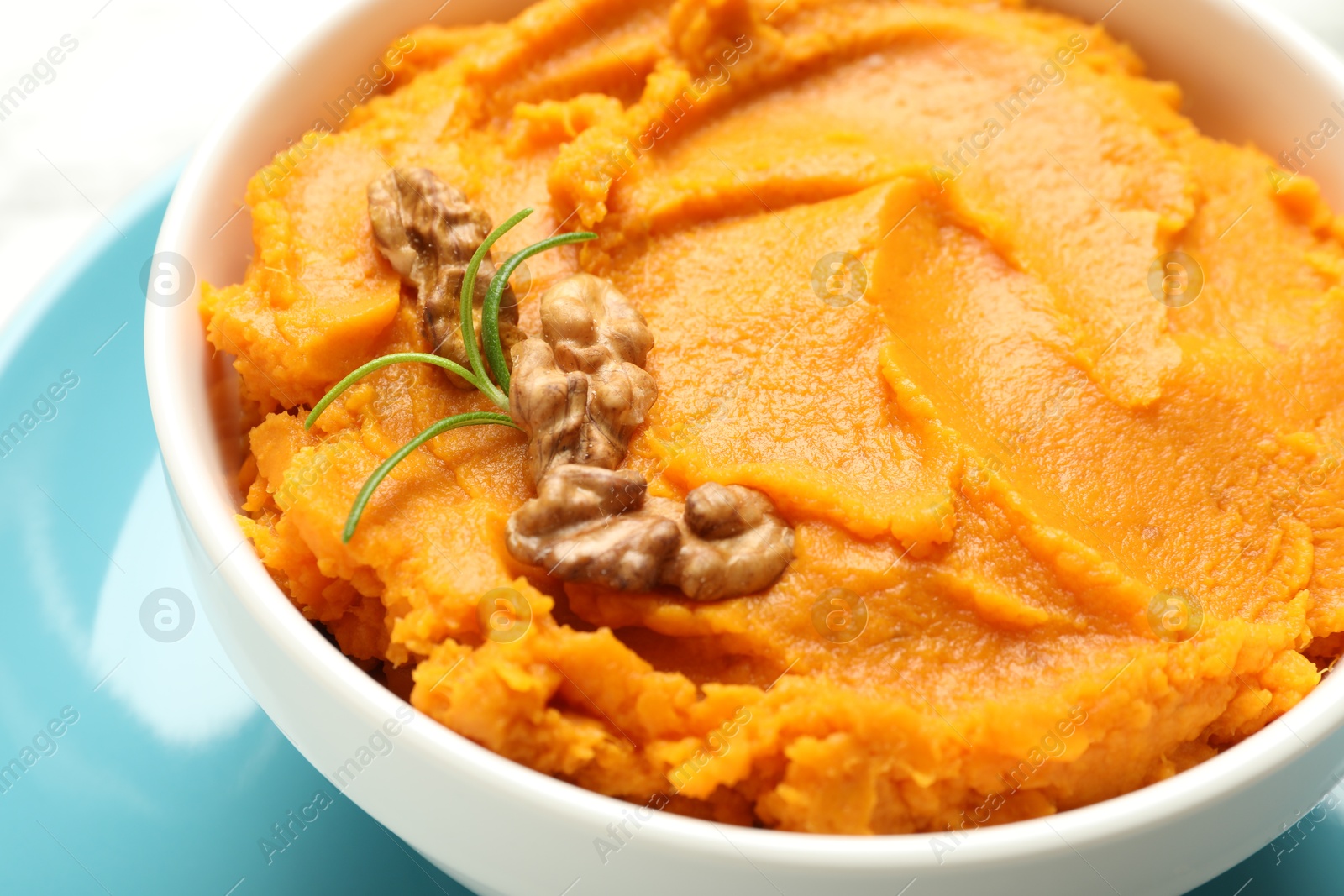 Photo of Delicious mashed sweet potatoes with walnuts in bowl on table, closeup