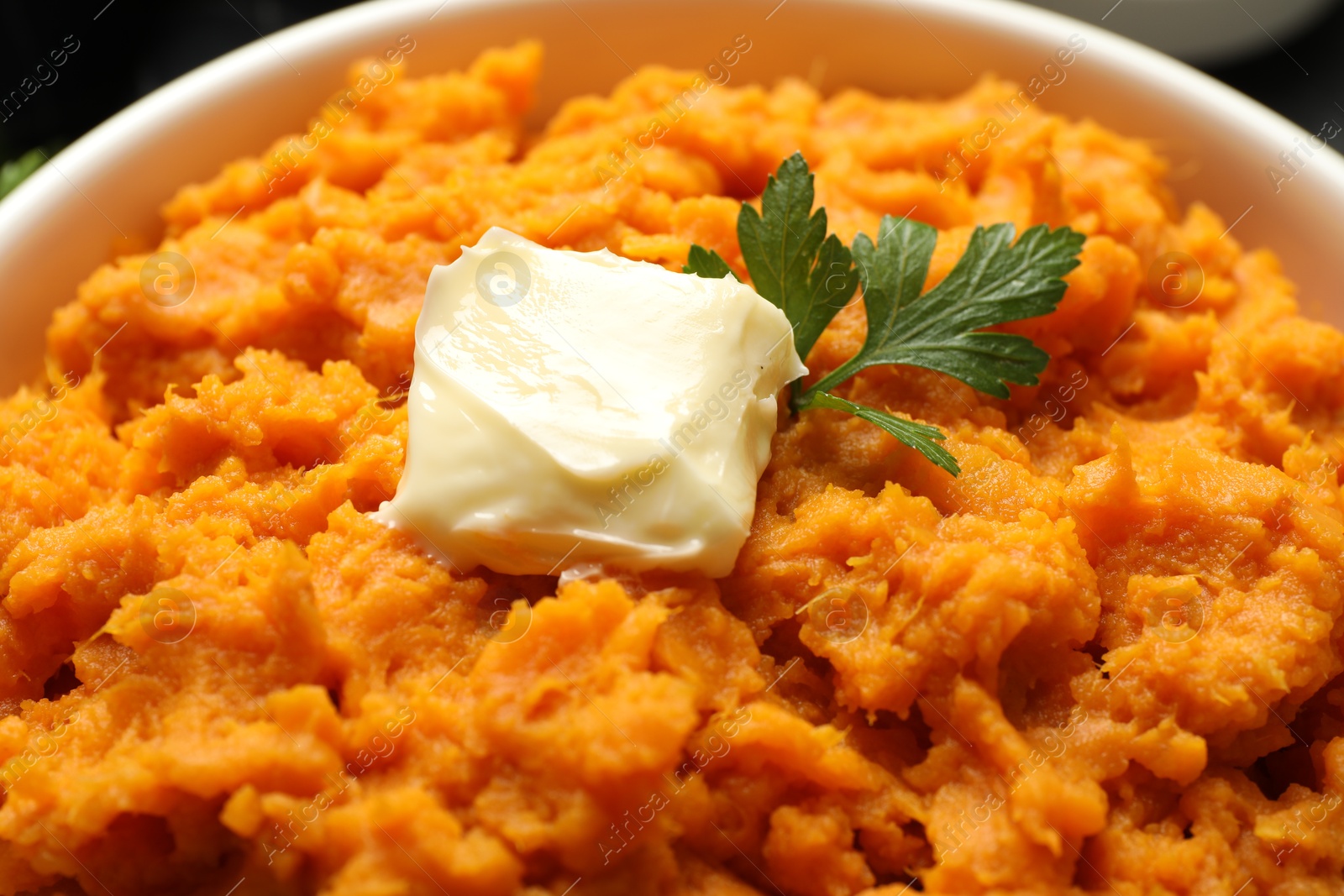 Photo of Delicious mashed sweet potatoes with butter and parsley in bowl, closeup