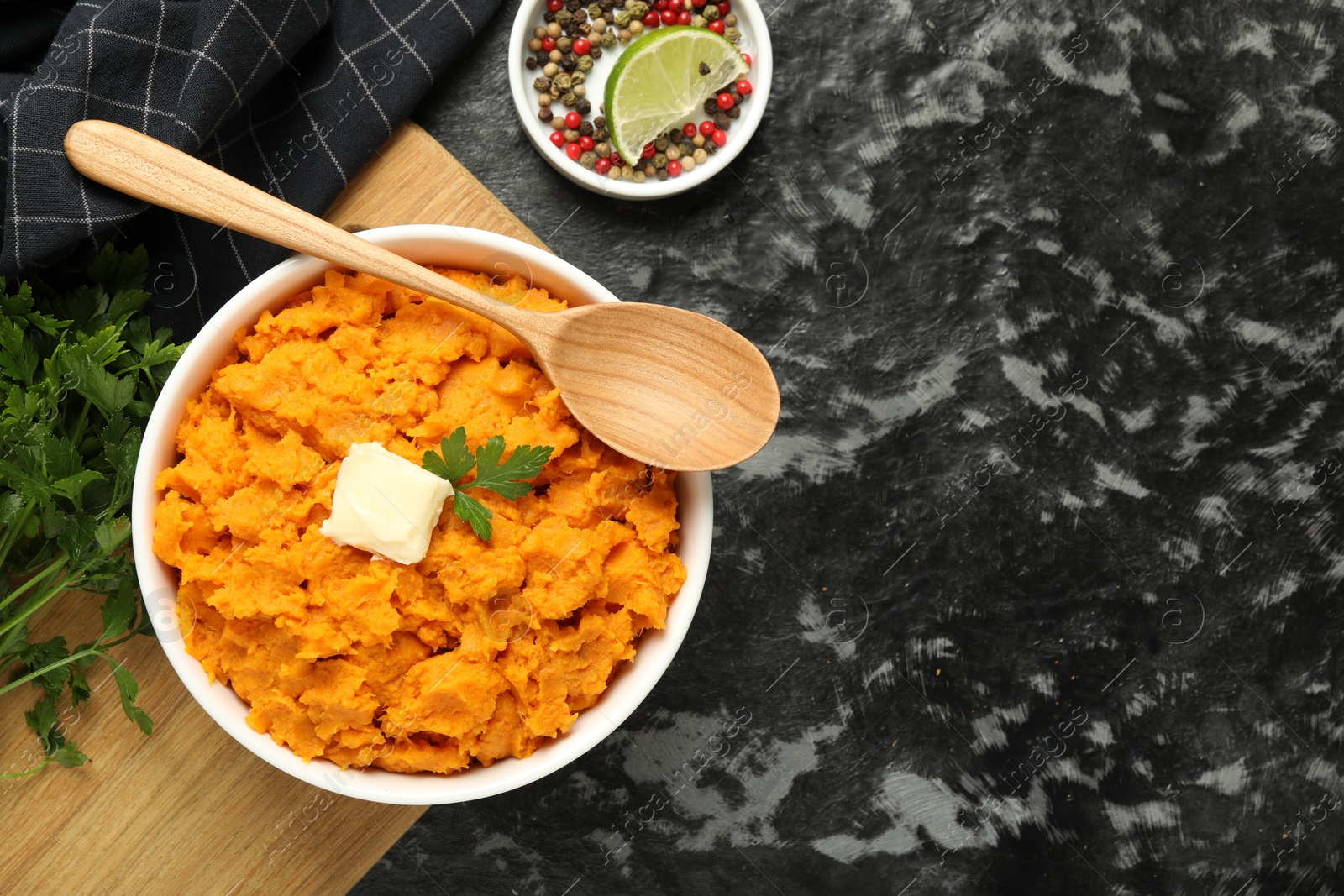 Photo of Delicious mashed sweet potatoes with butter, spices and spoon on dark table, top view. Space for text