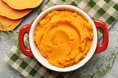 Photo of Delicious mashed sweet potatoes in pot, vegetable and microgreens on grey table, top view