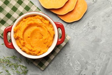 Delicious mashed sweet potatoes in pot, vegetable and microgreens on grey table, top view. Space for text