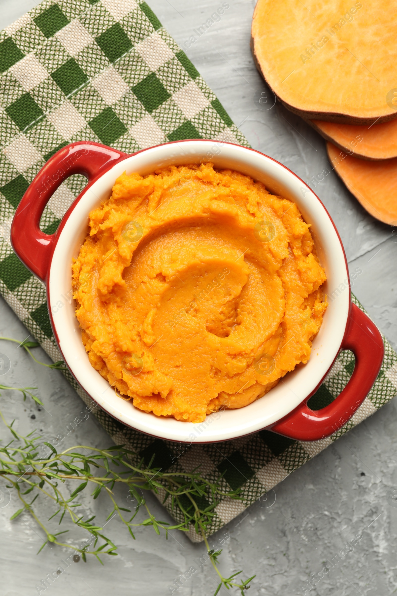 Photo of Delicious mashed sweet potatoes in pot, vegetable and microgreens on grey table, top view