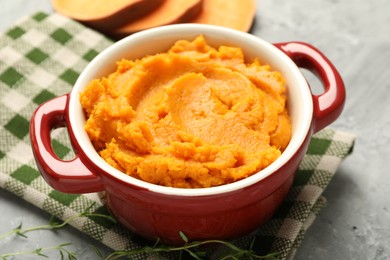 Delicious mashed sweet potatoes in pot and microgreens on grey table, closeup