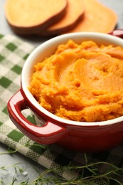 Delicious mashed sweet potatoes in pot and microgreens on table, closeup