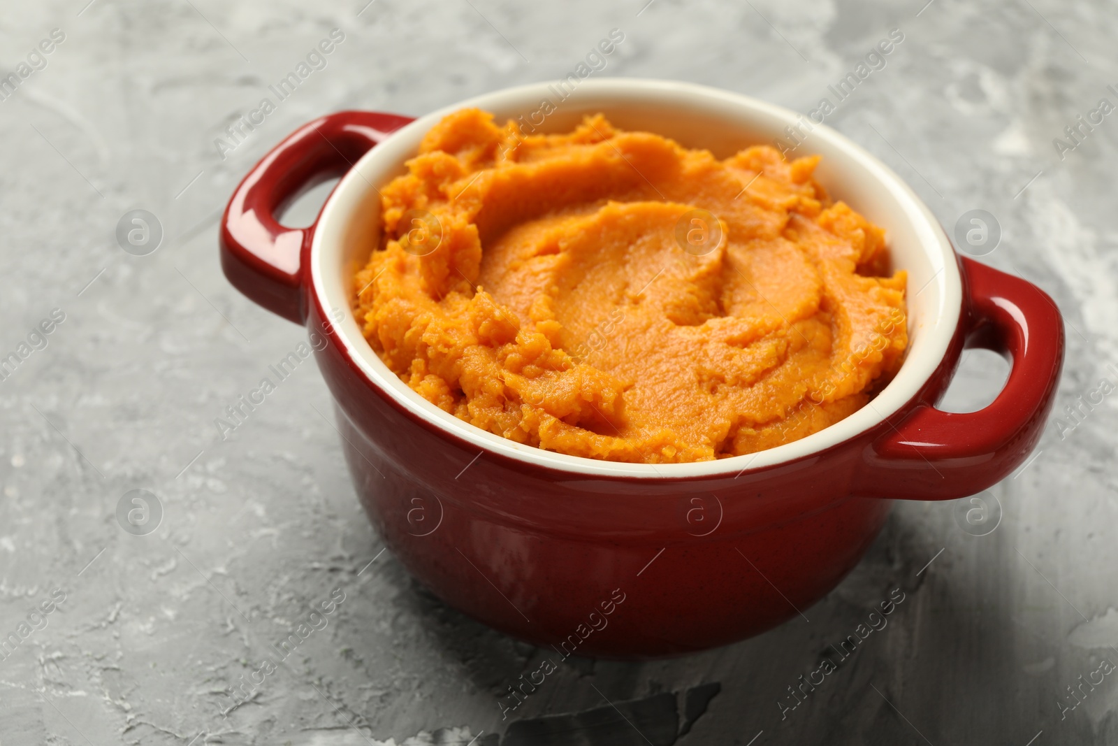 Photo of Delicious mashed sweet potatoes in pot on grey table, closeup