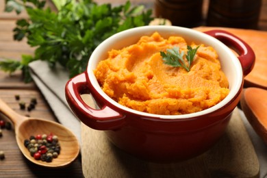 Delicious mashed sweet potatoes in pot and spices on wooden table, closeup