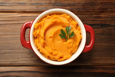 Photo of Delicious mashed sweet potatoes with parsley in pot on wooden table, top view