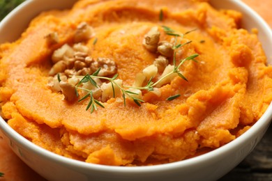 Delicious mashed sweet potatoes and walnuts in bowl on table, closeup