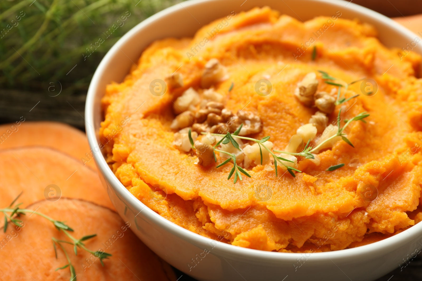 Photo of Delicious mashed sweet potatoes in bowl and vegetable on table, closeup