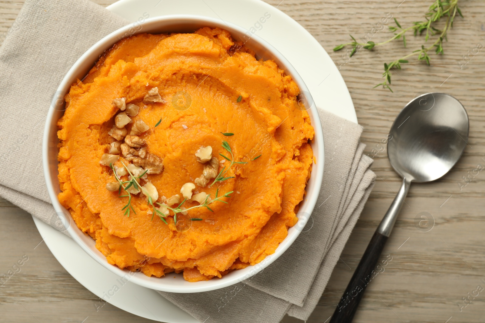 Photo of Delicious mashed sweet potatoes in bowl and spoon on wooden table, top view