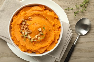 Photo of Delicious mashed sweet potatoes in bowl and spoon on wooden table, top view