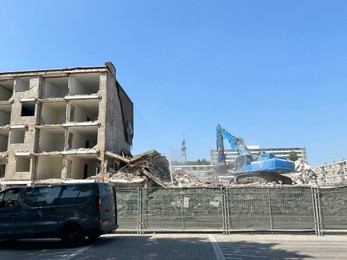 Demolition of building with excavator under blue sky