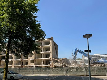 Demolition of building with excavator under blue sky