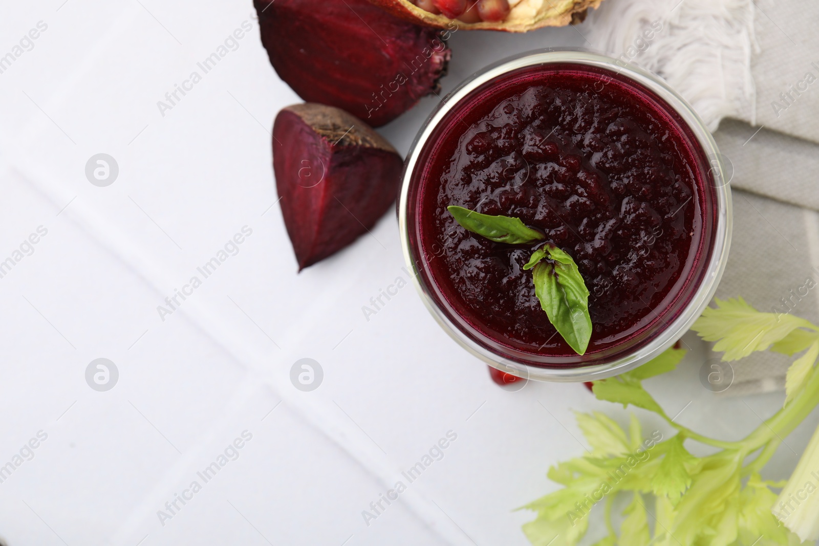 Photo of Fresh beetroot smoothie with mint in glass on white tiled table, flat lay. Space for text