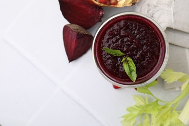 Fresh beetroot smoothie with mint in glass on white tiled table, flat lay. Space for text