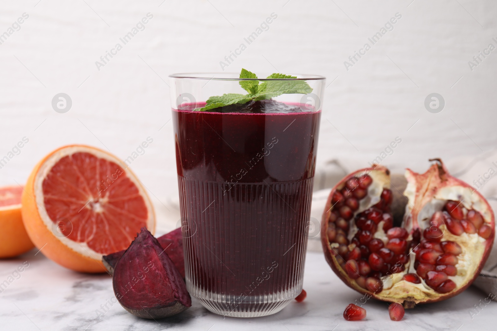 Photo of Fresh beetroot smoothie with mint in glass on white marble table