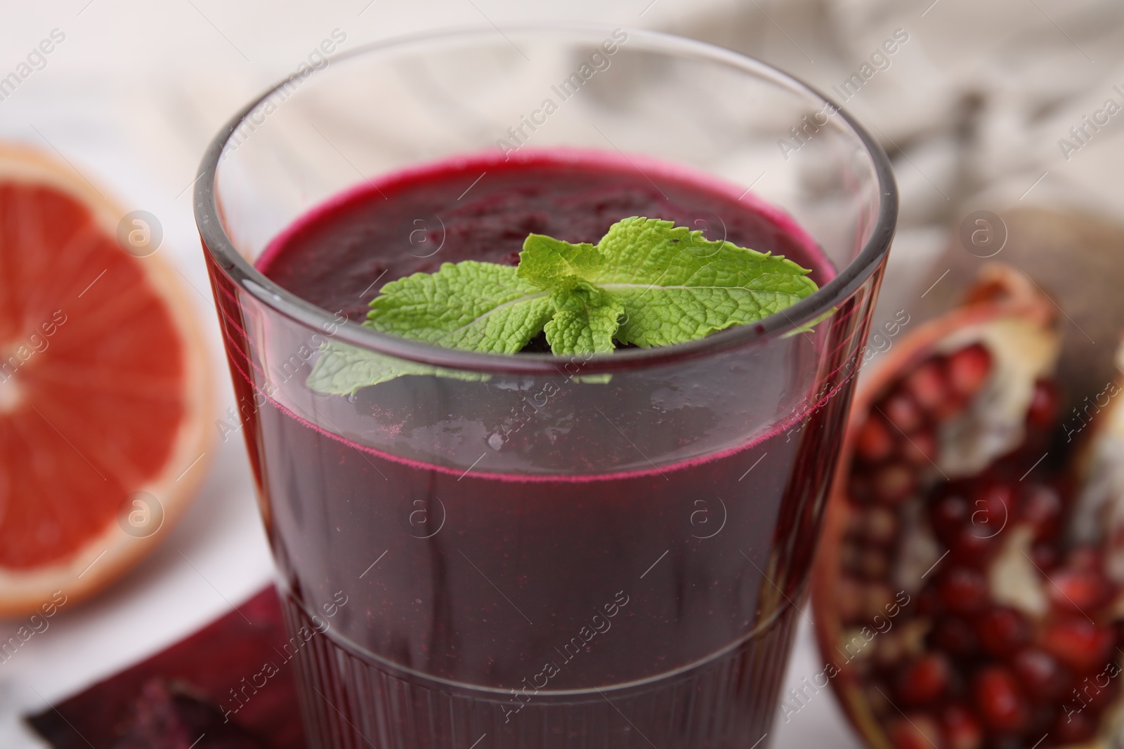 Photo of Fresh beetroot smoothie with mint in glass on table, closeup