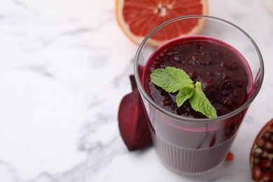 Fresh beetroot smoothie with mint in glass on white marble table, closeup. Space for text