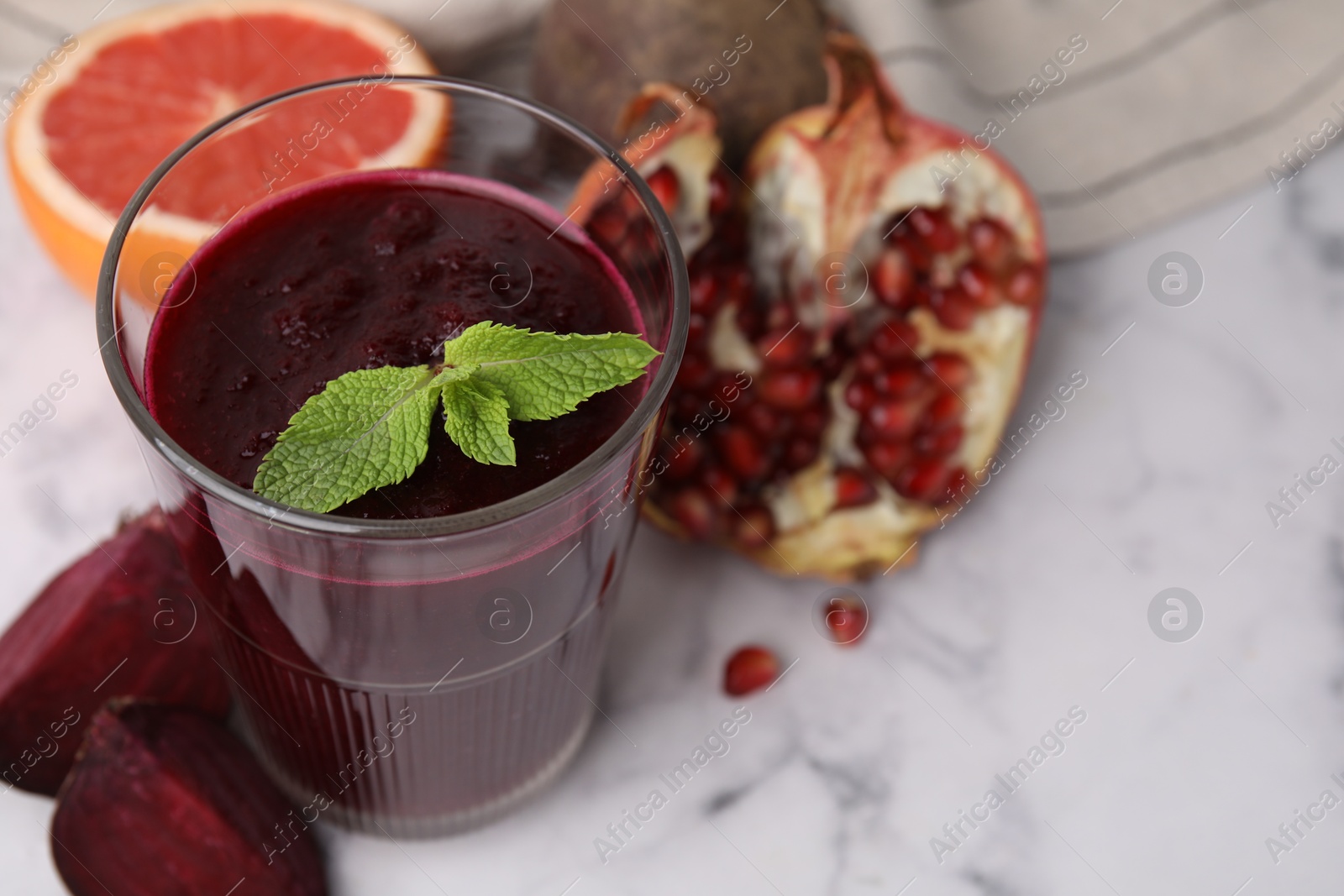 Photo of Fresh beetroot smoothie with mint in glass on white marble table, closeup. Space for text