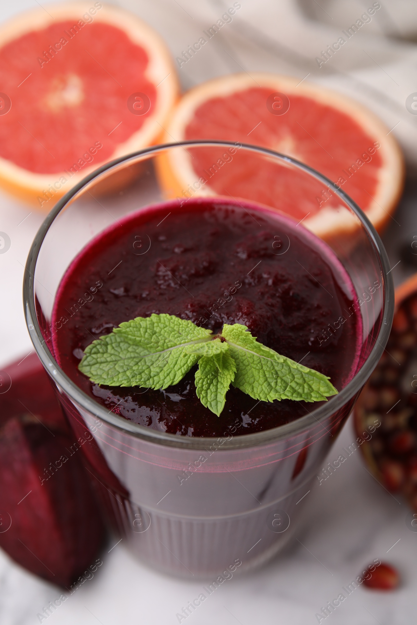 Photo of Fresh beetroot smoothie with mint in glass on white table, closeup