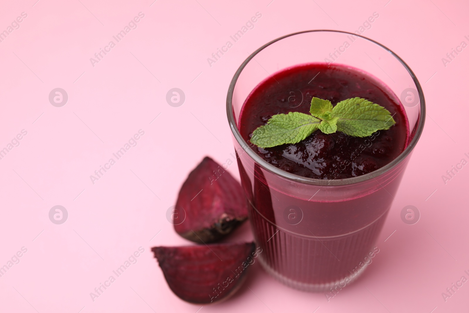 Photo of Fresh beetroot smoothie in glass and beet on pink table, closeup. Space for text