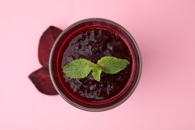 Photo of Fresh beetroot smoothie and mint in glass on pink table, top view. Vegan drink