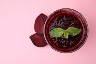 Fresh beetroot smoothie and mint in glass on pink table, top view. Space for text