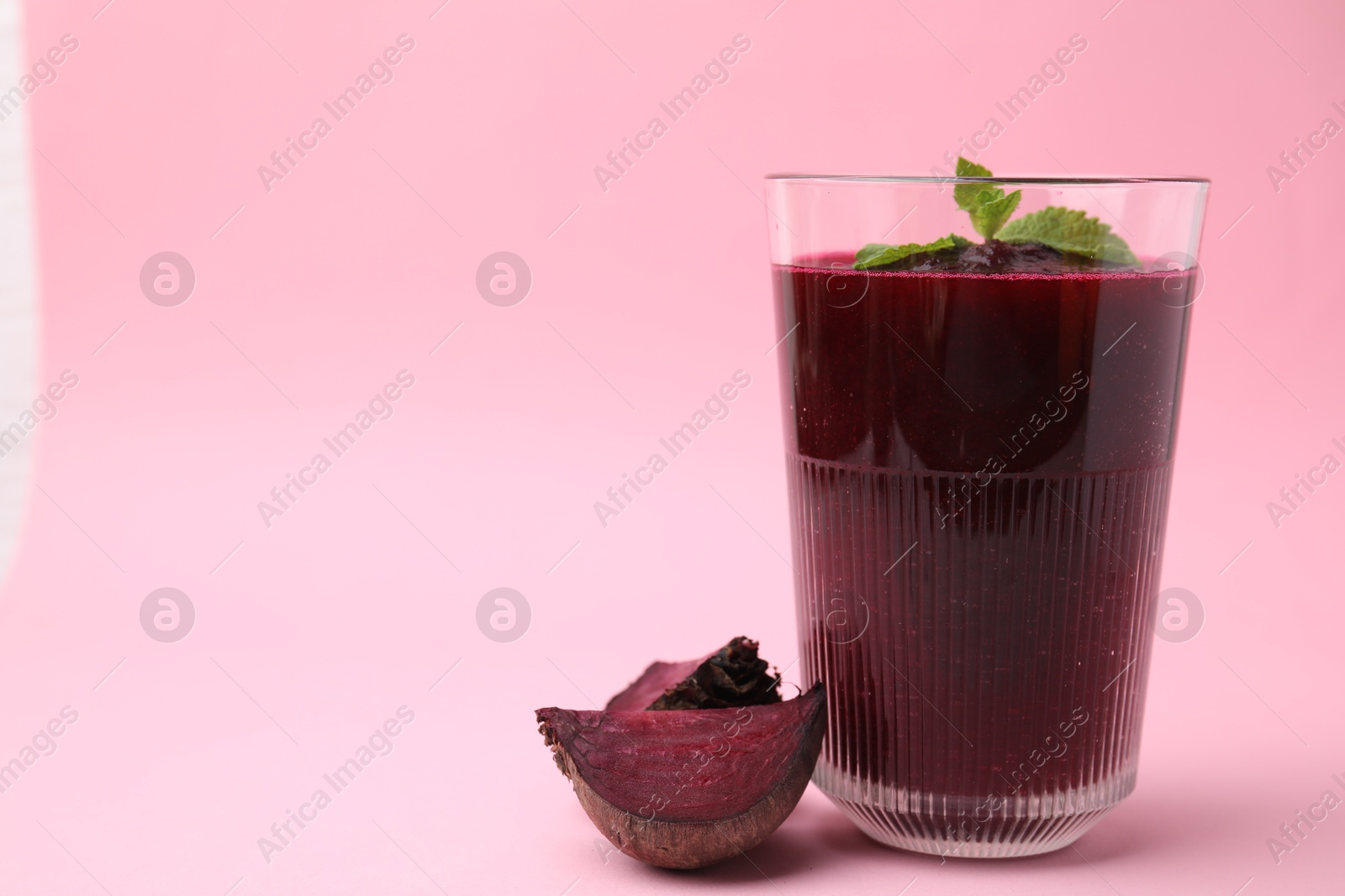 Photo of Fresh beetroot smoothie in glass and beet on pink table, closeup. Space for text