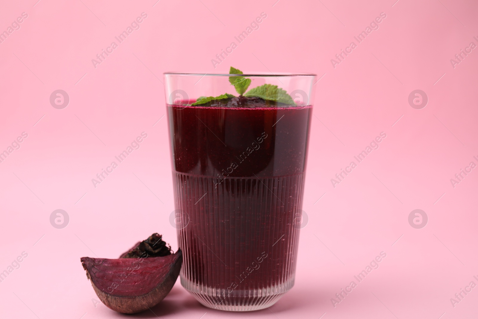 Photo of Fresh beetroot smoothie in glass and beet on pink table